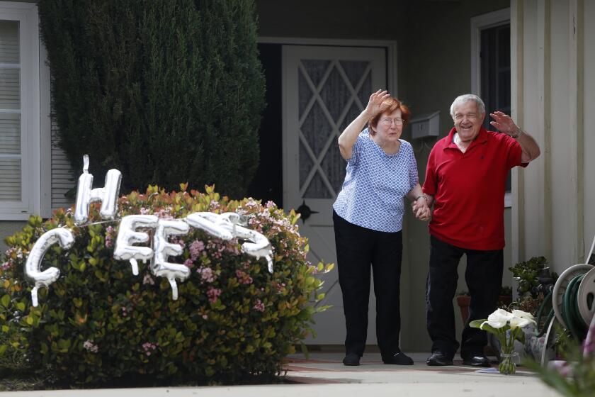 LOS ANGELES, CA-MARCH 25, 2020: Libby and Harry Palakow come out from their home to a small crowd of neighbors who gathered to celebrate their 70th wedding anniversary in Granada Hills on March 25, 2020 in Los Angeles, California. With restrictions to how close people can be to help prevent the spread of the coronavirus, neighbors celebrated from outside and stood apart from each other. (Photo By Dania Maxwell / Los Angeles Times)