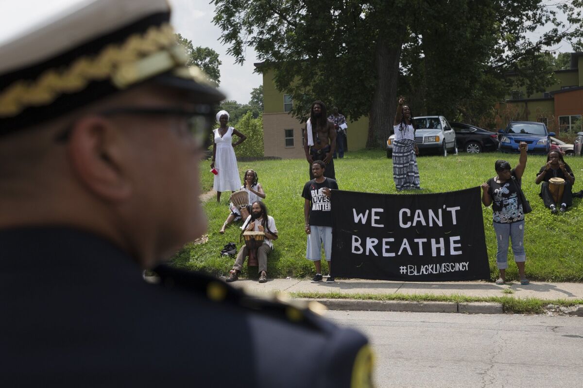 Cincinnati Police Chief Jeffrey Blackwell stands across the street from protesters outside the funeral service for Samuel DuBose this week. On Wednesday, a University of Cincinnati policeman was indicted on a murder charge in DuBose's death.