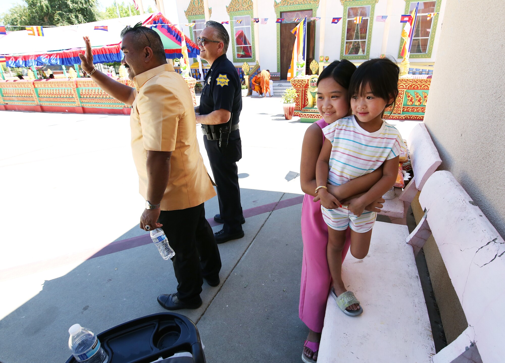 Danny Kim, left, watches a parade for the temple abbot with Melinda and Alexa Hok.