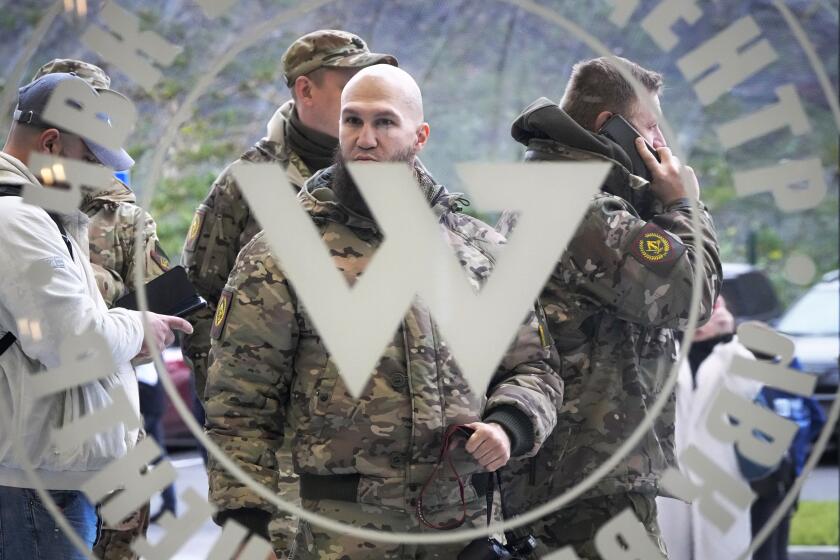 Visitors wearing military camouflage stand at the entrance of the 'PMC Wagner Centre', which is associated with businessman and founder of the Wagner private military group Yevgeny Prigozhin, during the official opening of the office block during National Unity Day, in St. Petersburg, Russia, Friday, Nov. 4, 2022. (AP Photo/Dmitri Lovetsky)