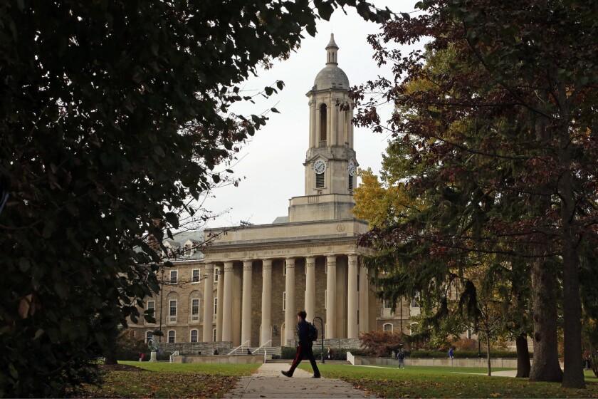 FILE- People walk by Old Main on the Penn State University main campus on Nov. 9, 2017 in State College, Pa. Applying to college is rarely easy, but applicants in 2022 are faced with one additional challenge: creating a compelling college application after nearly two years of disruptions as a result of the pandemic. (AP Photo/Gene J. Puskar, File)