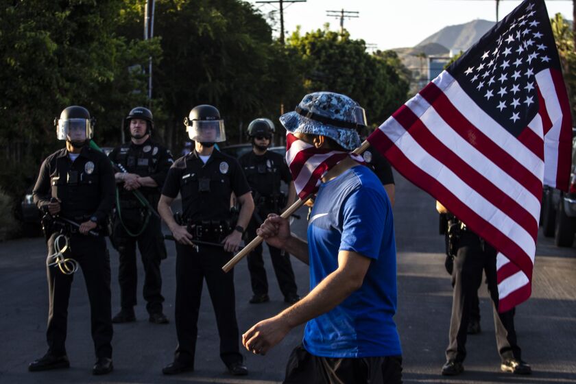 HOLLYWOOD, CA - JUNE 03: Protester John Michaels carries an American flag through a residential neighborhood past a LAPD skirmish line during march on Wednesday, June 3, 2020 in Hollywood, CA. (Brian van der Brug / Los Angeles Times)