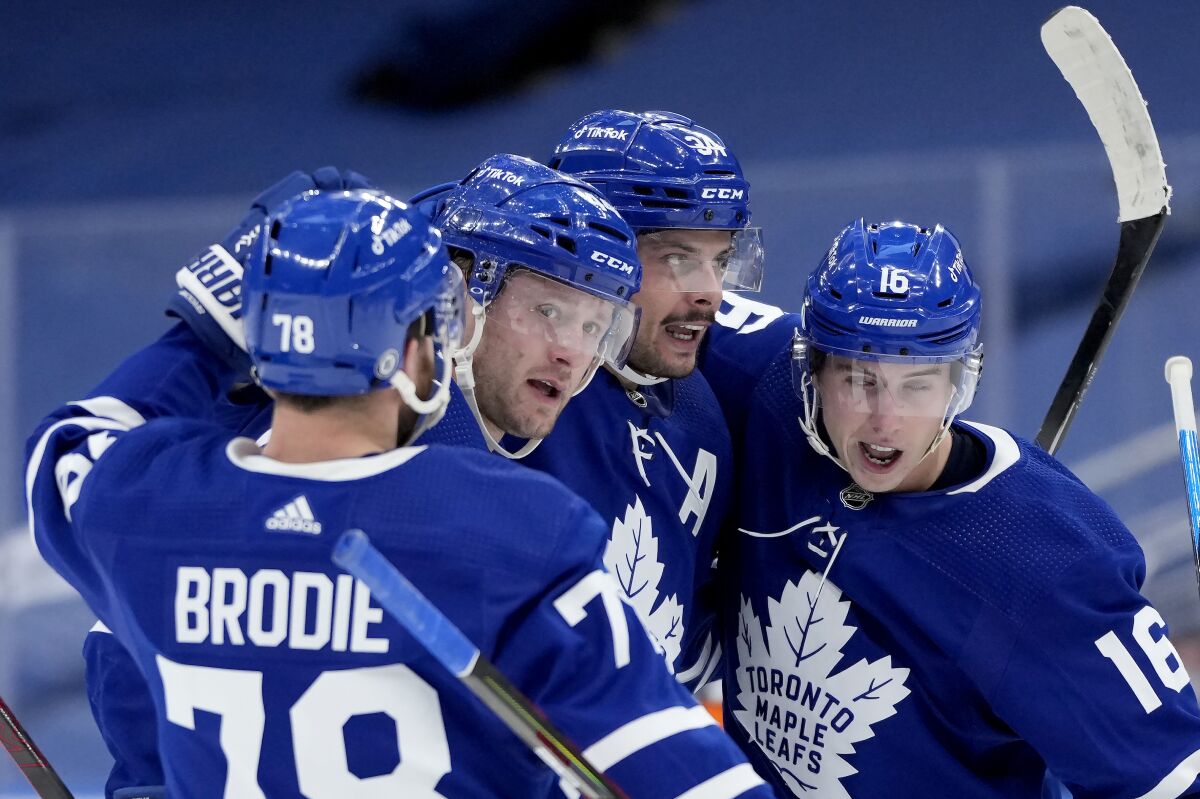 Toronto Maple Leafs center Auston Matthews (34) celebrates his goal with teammates TJ Brodie (78), Morgan Rielly (44) and Mitchell Marner (16) during the second period of an NHL hockey game against the Carolina Hurricanes, in Toronto, Monday, Feb. 7, 2022. (Frank Gunn/The Canadian Press via AP)