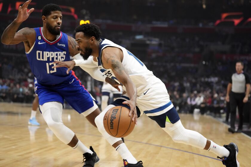 Minnesota Timberwolves guard Mike Conley, right, drives against Los Angeles Clippers forward Paul George (13) during the first half of an NBA basketball game Tuesday, Feb. 28, 2023, in Los Angeles. (AP Photo/Marcio Jose Sanchez)