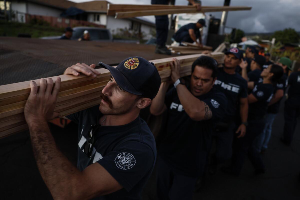 Volunteer firefighters carry lumber.