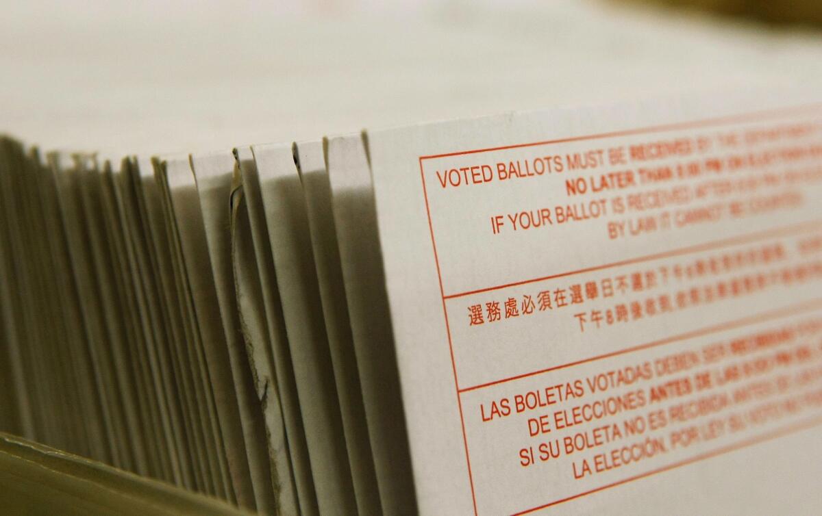 A stack of vote-by-mail ballots sit in a box 