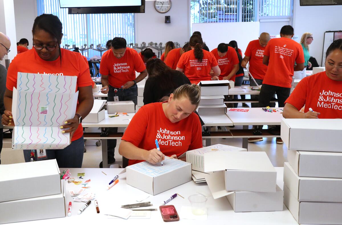 Volunteers draw cartoons on hygiene kit boxes during the Johnson & Johnson MedTech annual Week of Caring.