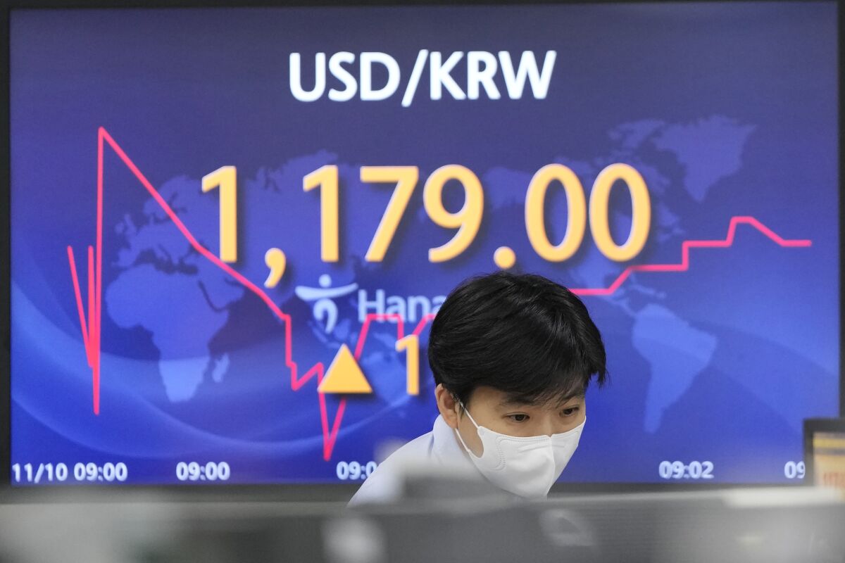 A currency trader watches computer monitors near a screen showing the foreign exchange rate between U.S. dollar and South Korean won at a foreign exchange dealing room in Seoul, South Korea, Wednesday, Nov. 10, 2021. Asian shares fell Wednesday, tracking Wall Street’s retreat, with Chinese benchmarks leading the decline after the government reported a surge in inflation in October. (AP Photo/Lee Jin-man)