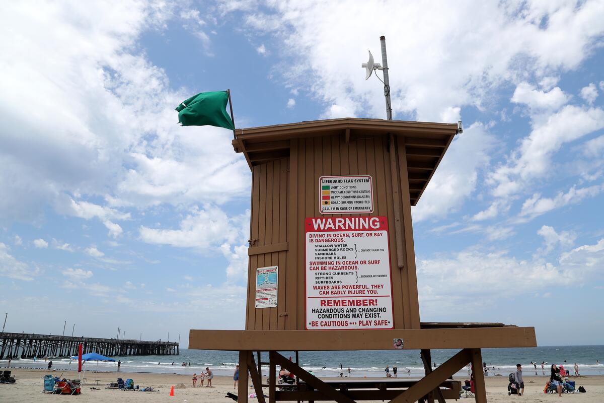 A green flag posted on a lifeguard tower indicates light conditions.
