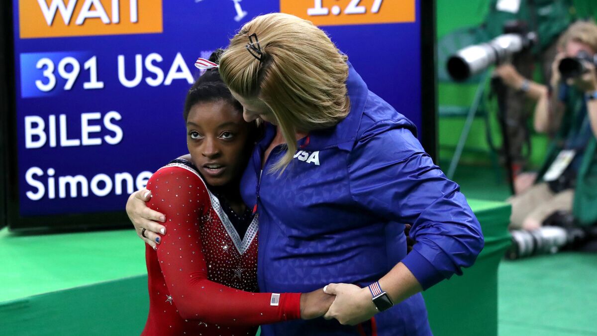 American gymnast Simone Biles is embraced by her coach, Aimee Boorman, after a disappointing performance on the balance beam during the individual finals on Monday.