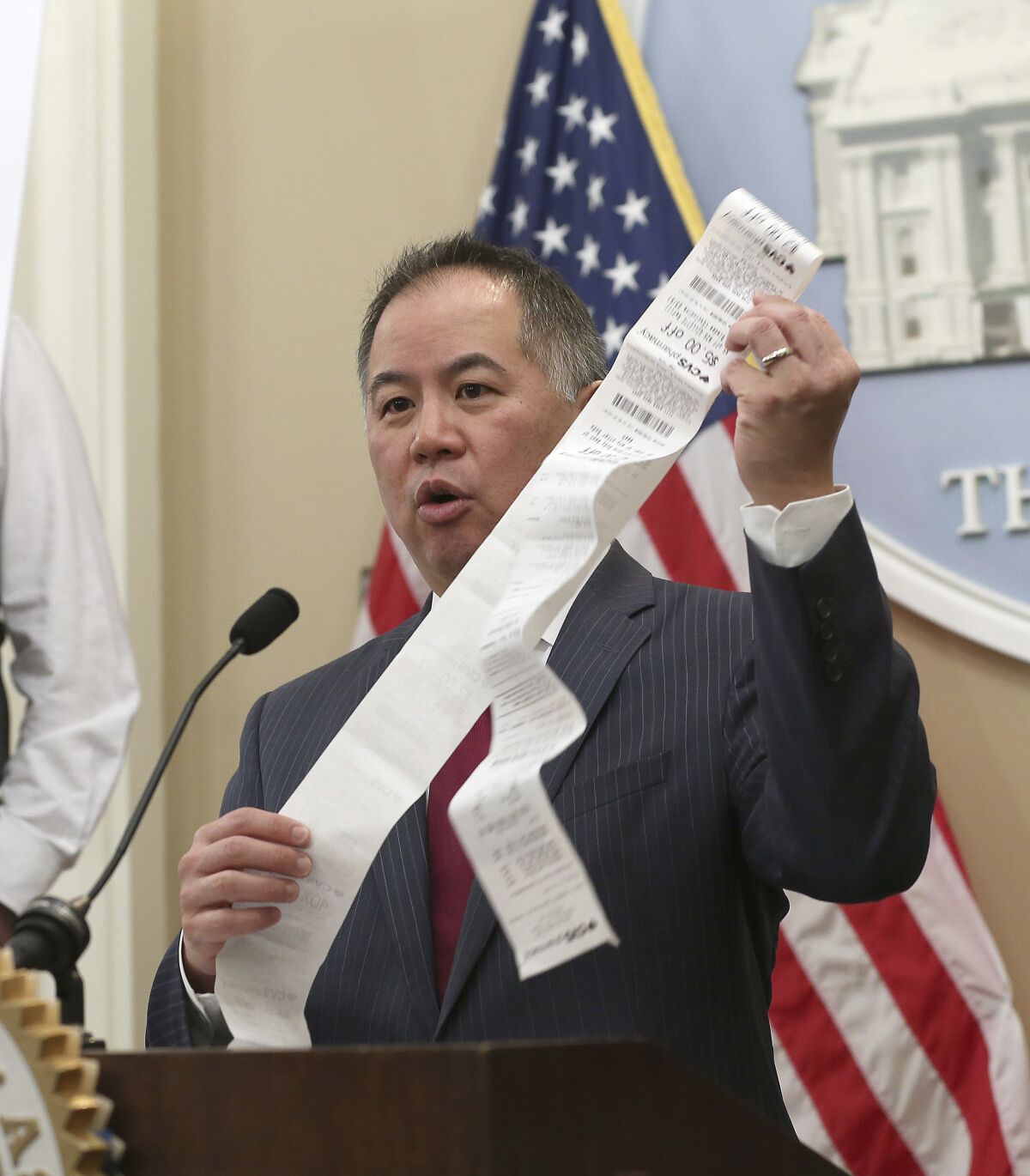 Assemblyman Phil Ting (D-San Francisco) holds a long paper receipt.