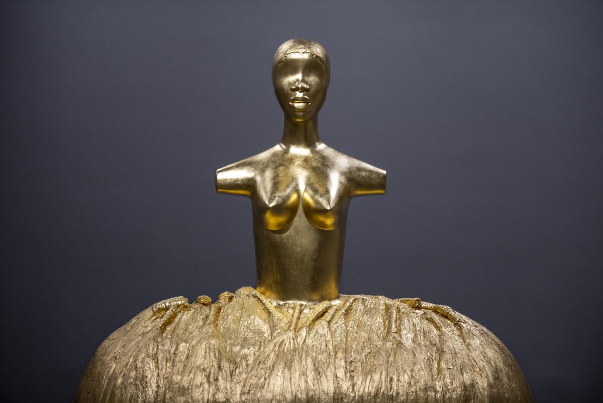Simone Leigh's sculpture "Cupboard," which depicts an armless, golden female form in a billowing skirt.