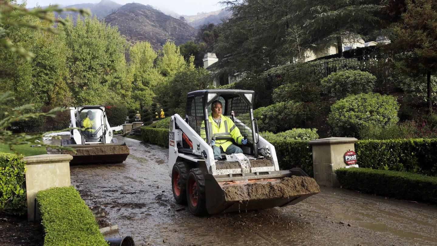 Crews work to clear mud from a home in the 1100 block of Easley Canyon Road on Friday morning.