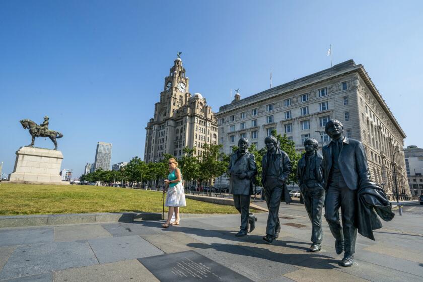 The Beatles statues and Royal Liver Building, centre, on the waterfront area of Liverpool, which has been removed from the World Heritage List Wednesday July 21, 2021. The UN World Heritage committee found developments including the new Everton soccer stadium threatened the value of the city's waterfront. (Peter Byrne/PA via AP)