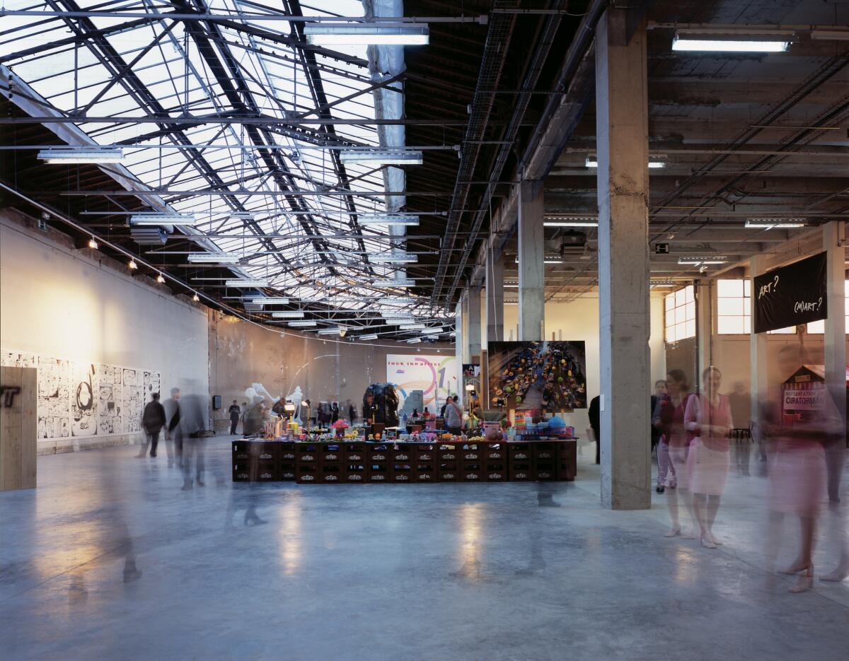 A large industrial space supported by reinforced concrete columns features a long skylight overhead