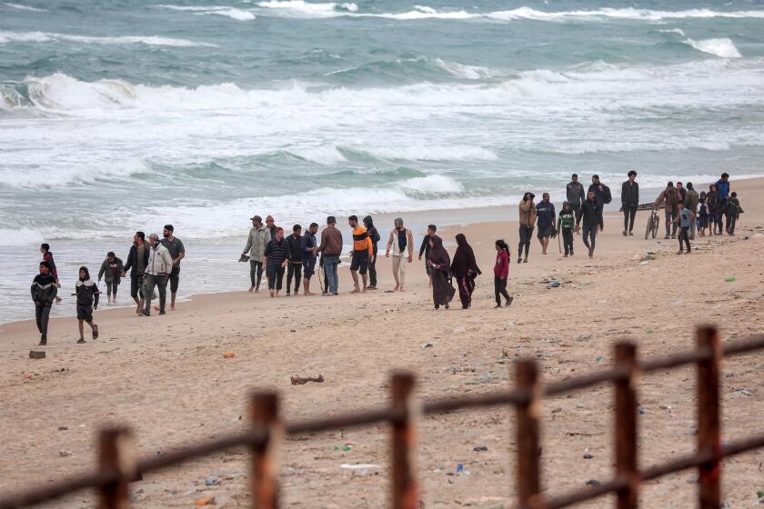 Palestinians fleeing from the area walk along the seashore as they arrive at the Nuseirat refugee camp.