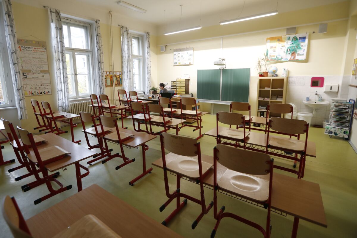 A teacher sits in an empty classroom and prepares materials for children at a closed school in Prague, Czech Republic, Wednesday, Oct. 14, 2020. Amid widespread efforts to curb the new wave of coronavirus infections in one of the hardest hit European countries, the Czech Republic closed again all its schools on Wednesday. (AP Photo/Petr David Josek)