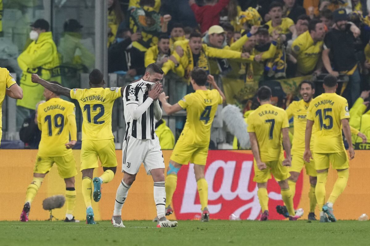 Juventus' Mattia De Sciglio gestures as Villarreal's Pau Torres, fourth from right, celebrates with his teammate Gerard Moreno after scoring his side's second goal during the Champions League, round of 16, second leg soccer match between Juventus and Villarreal at the Allianz stadium in Turin, Italy, Wednesday, March 16, 2022. (AP Photo/Antonio Calanni)
