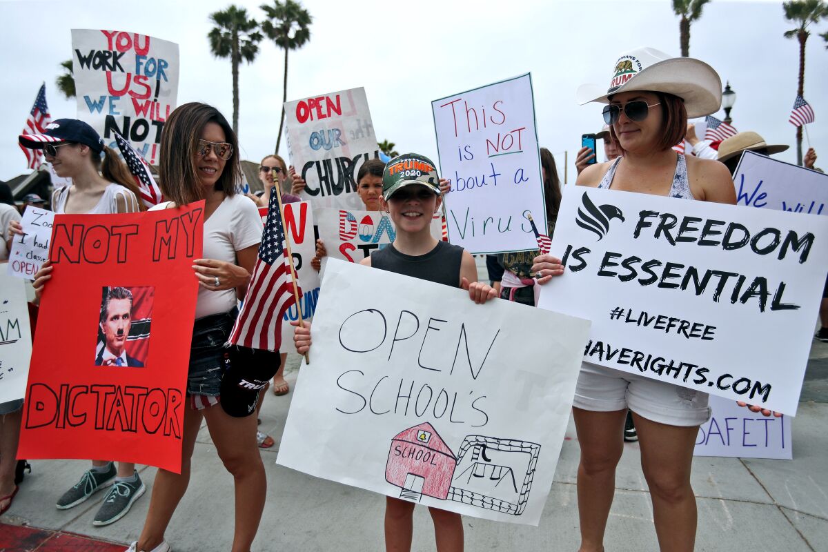A young protester holds a sign at Huntington Beach's Pier Plaza on May 9.