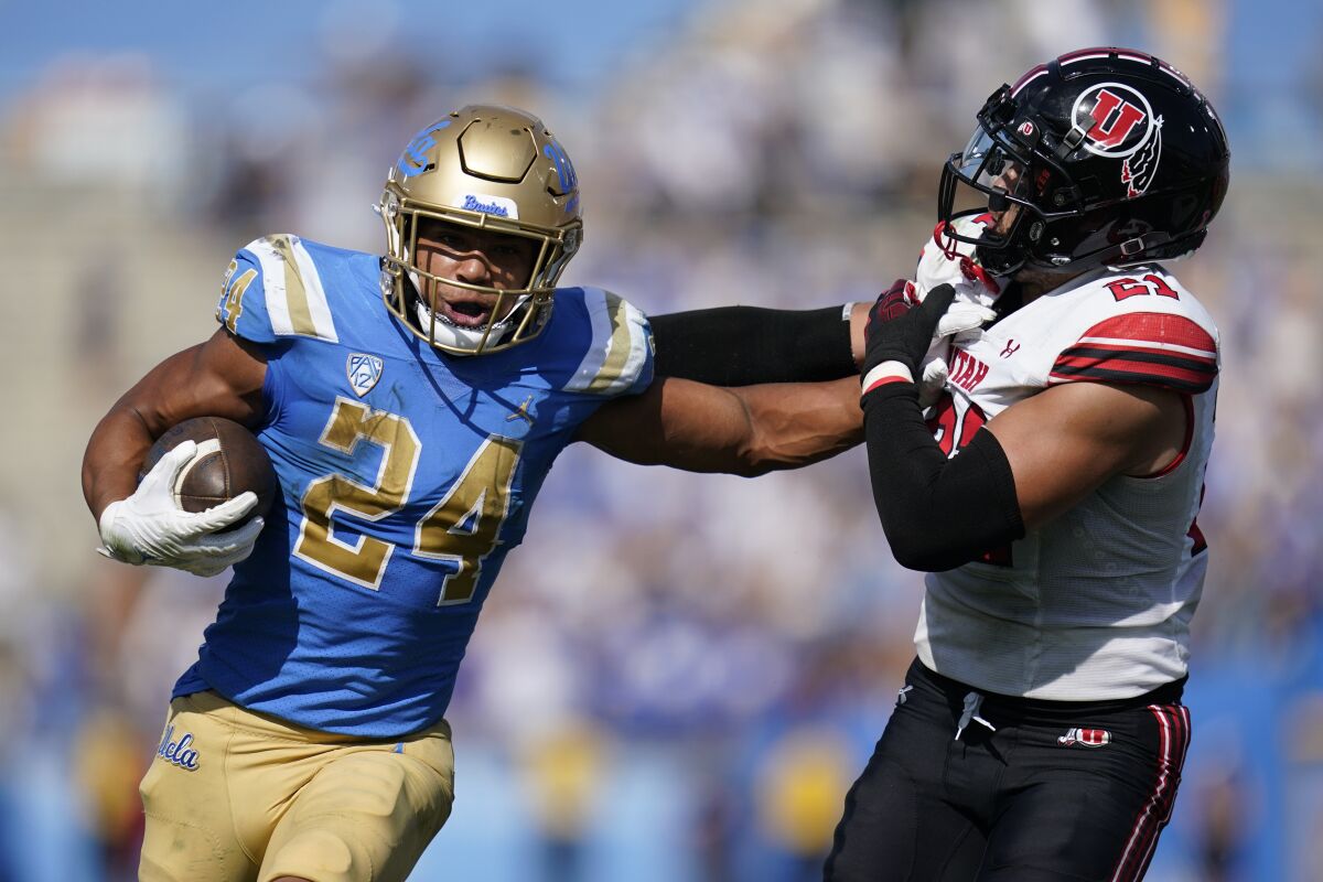 Le porteur de ballon de l'UCLA Zach Charbonnet, secondeur de l'Utah aux bras raides, Karene Reid, lors de la victoire 42-32 des Bruins le 8 octobre.