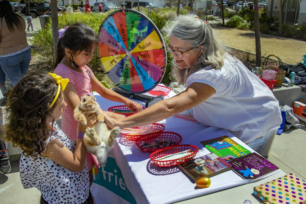  Cheryl Fletcher pats Candy Arredondo's bunny wearing an Easter bow during Costa Mesa's 2022 SpringFest.
