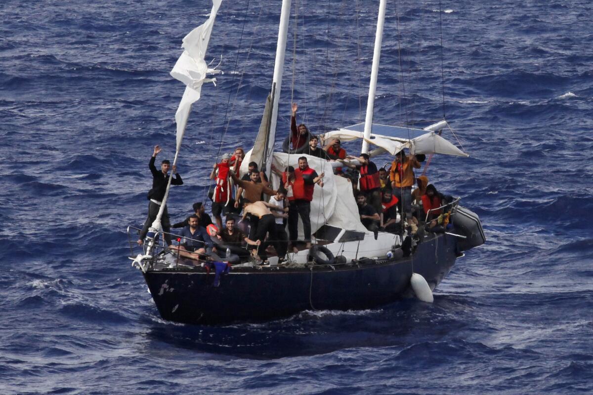 Migrants wave for help as they wait for the Italian coast guard to rescue them, on international waters in the Mediterranean Sea, Sunday, Sept. 12, 2021. (AP Photo/Samy Magdy)