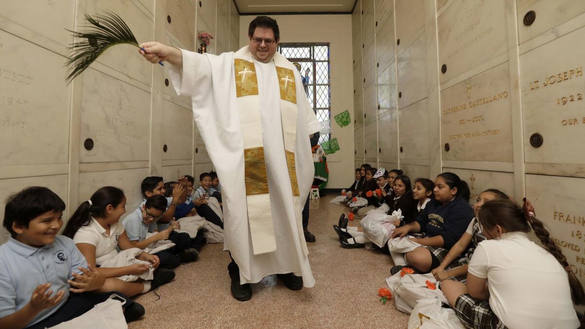 Friar Chris Bazyouros, director of the Office of Religious Education of the Archdiocese of Los Angeles, blesses students and the altar they made at Calvary Cemetery in East Los Angeles.