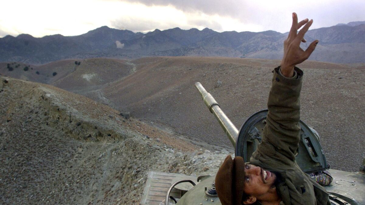 An Afghan soldier pops up from his tank to signal a U.S. warplane flying overhead