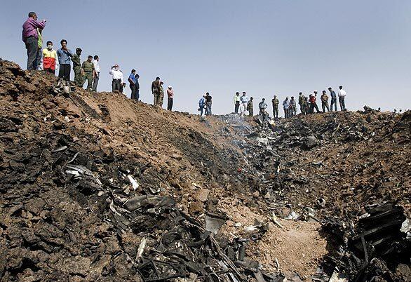 Iranians gather at the edge of a crater where a Caspian Airlines plane crashed into farmland near Qazvin, northwest of Tehran. The Iranian airliner en route to Armenia crashed, killing all 168 people on board.