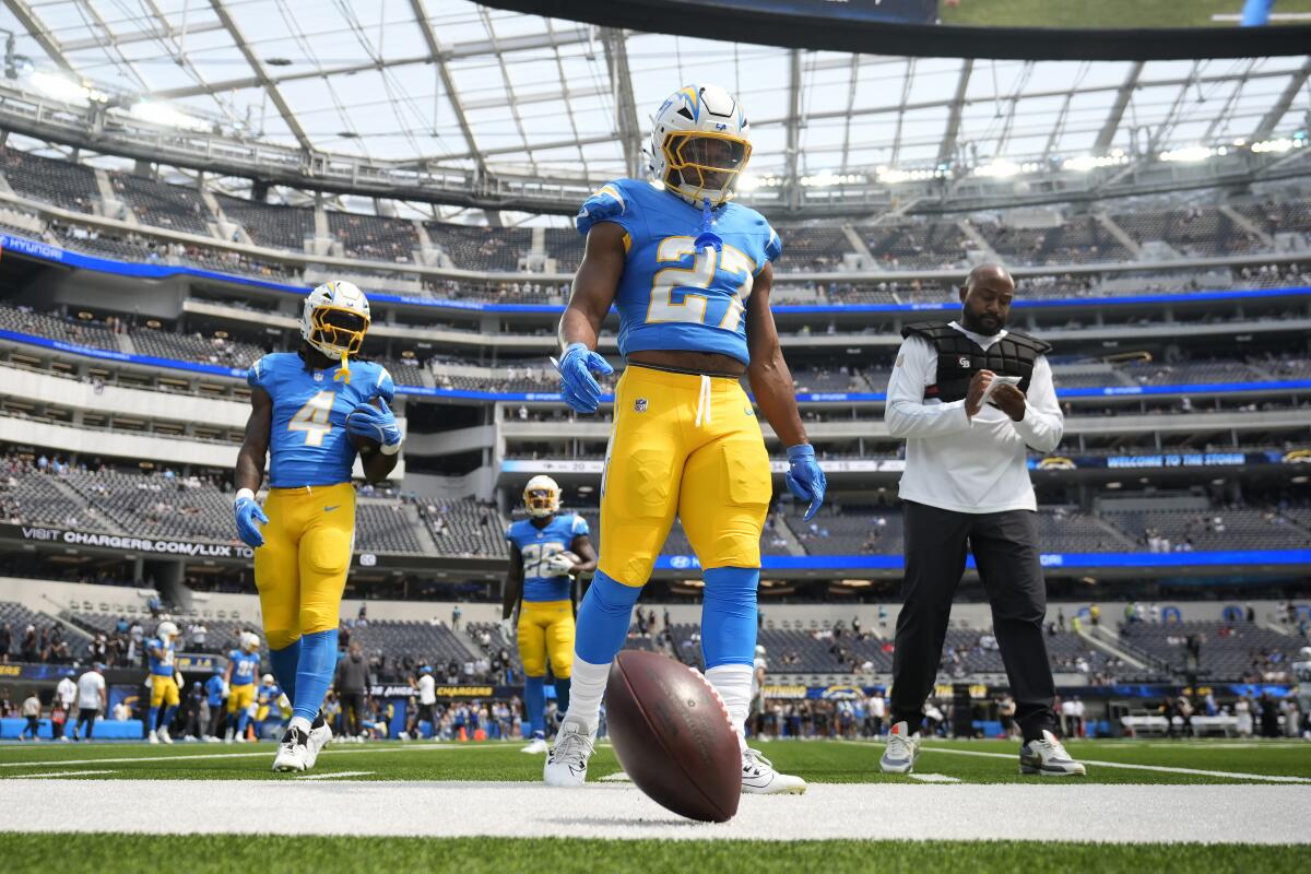 Chargers running backs  J.K. Dobbins (27) and Gus Edwards (4) walk on the field before their season opener.