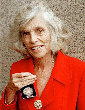 Eunice Kennedy Shriver holds a commemorative silver dollar coin minted in her honor. She was the first living woman to be honored with a commemorative U.S. coin--for her work in founding the Special Olympics.