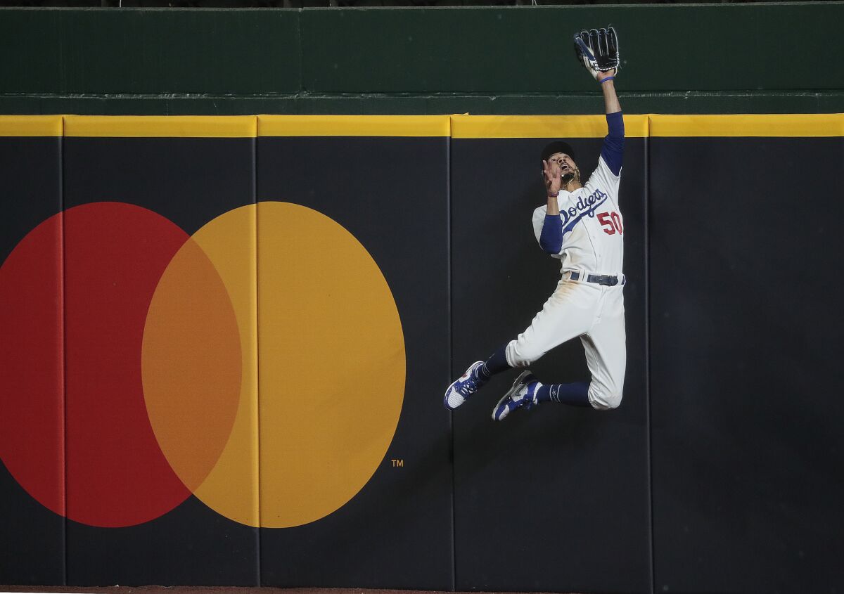 Mookie Betts leaps at the right field wall, extending his glove above the wall