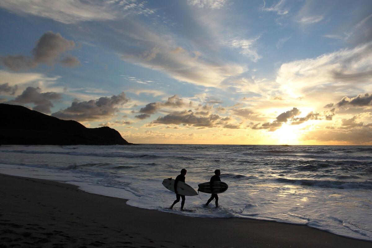 Men walk on the beach after surfing at Capo di Feno on the French Mediterranean island of Corsica.