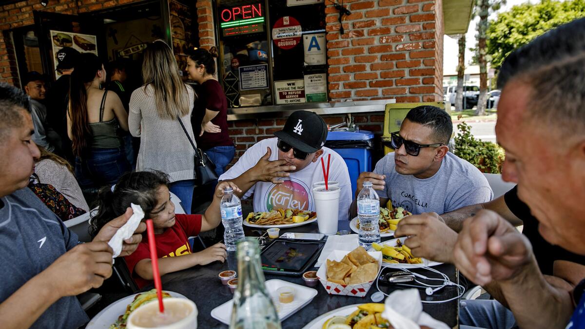 Frequent customers Omar Vasquez, from left, Olivia Vasquez, 3, Carlos Vasquez, Bill Lopez and Eddie Ruiz eat at Teddy's Tacos.