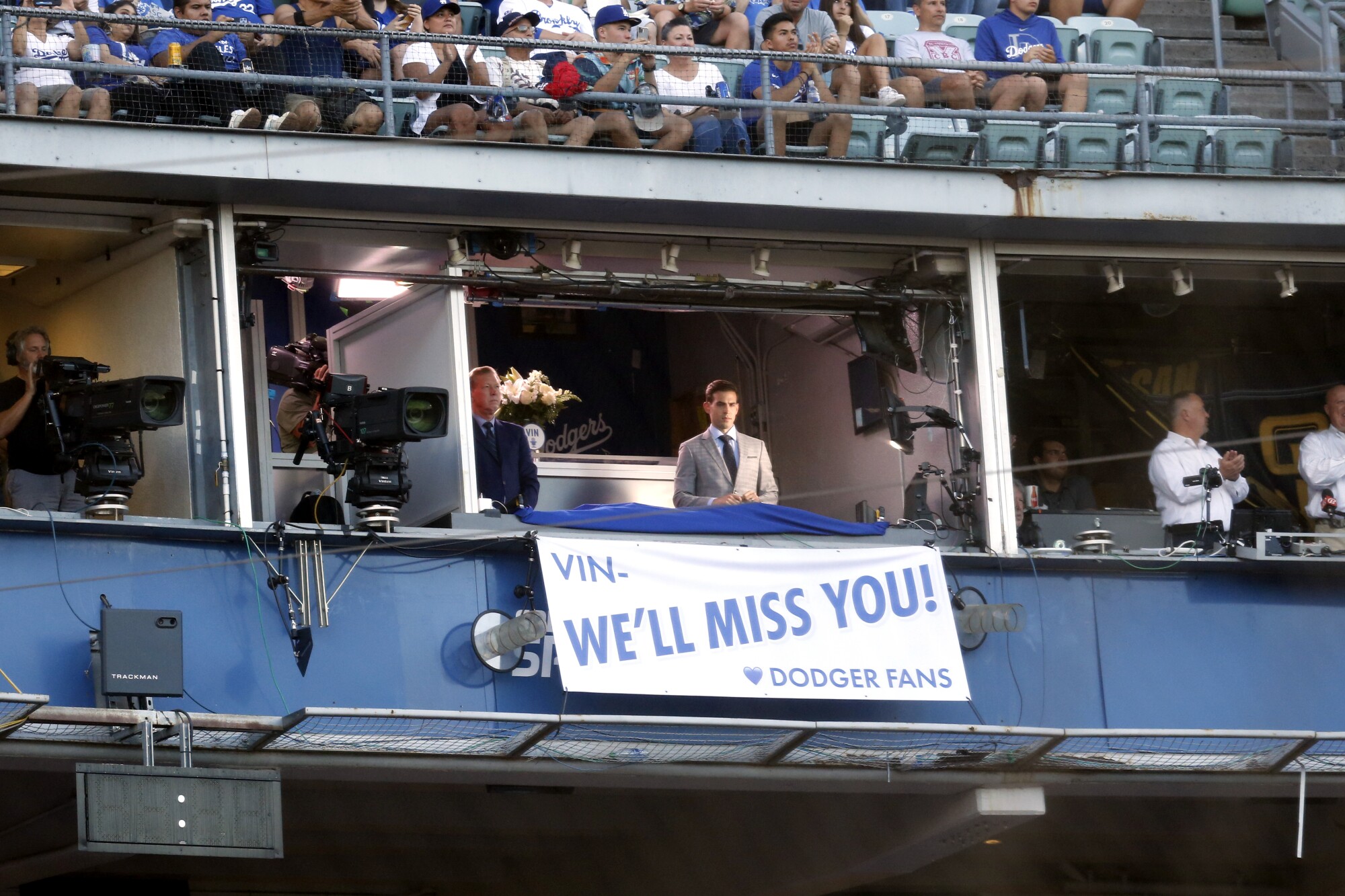 Broadcasters Orel Hershiser, left, and Joe Davis unveil a banner honoring Vin Scully.