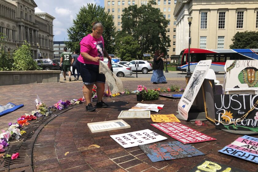 Amber Brown, a Louisville city bus driver, sets up Breonna Taylor artwork at a long-time protest site in Louisville, Ky., Aug. 24, 2020. Brown and others have demonstrated at the downtown public square for months, calling for police officers to be charged in the slaying of Taylor, who was shot in her home March 13. (AP Photo/Dylan Lovan)