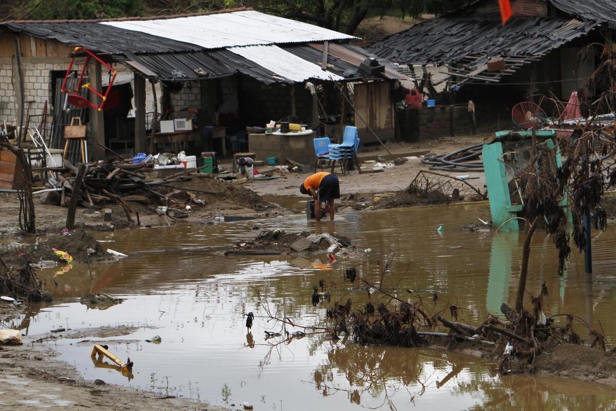 A resident whose home was flooded rinses away mud from his TV in Coyuca de Benitez, near Acapulco, on Wednesday. Raymond weakened from a hurricane to a tropical storm Wednesday and began moving away from Mexico's Pacific coast.