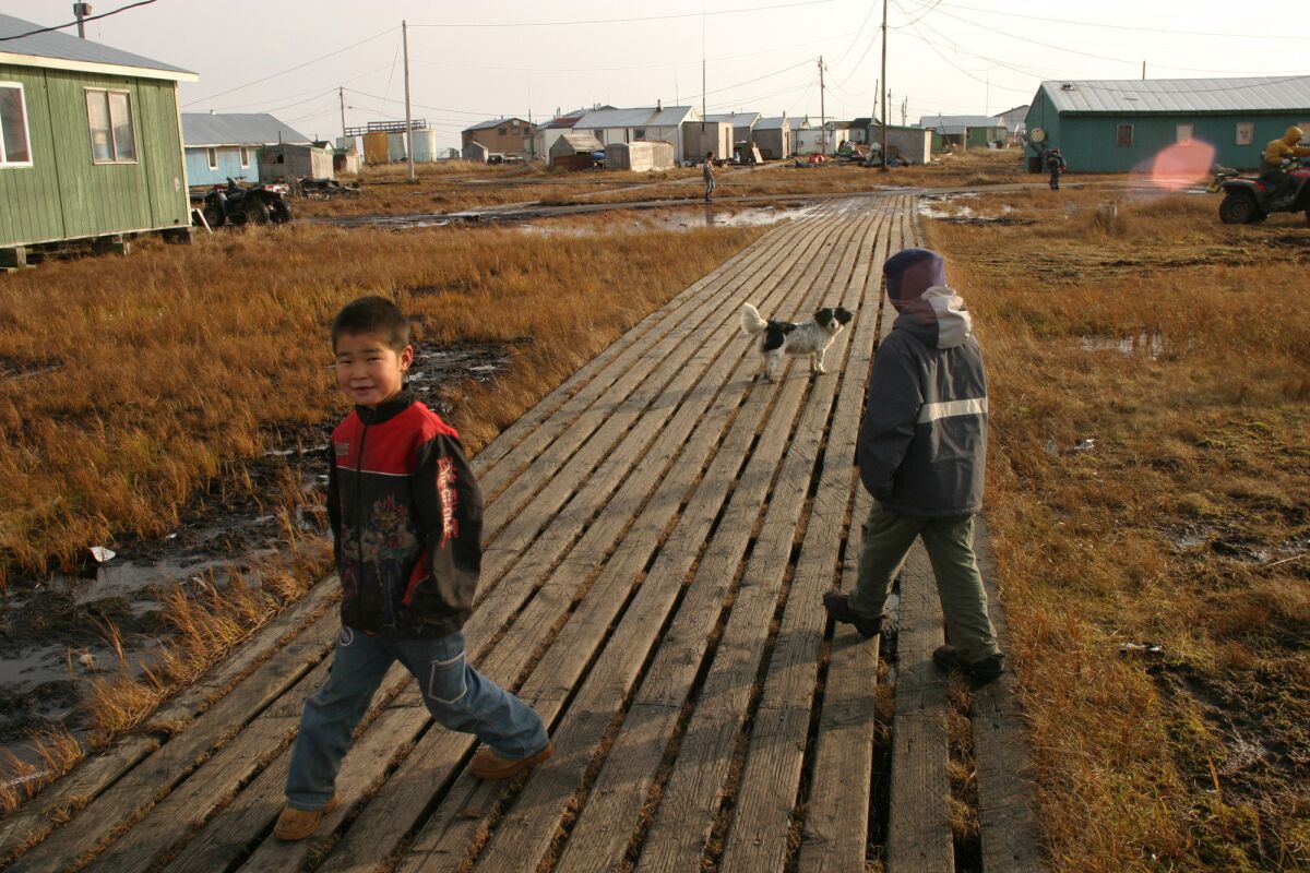 Two young boys walk along the boardwalk in the village of Newtok, Alaska in October of 2004.