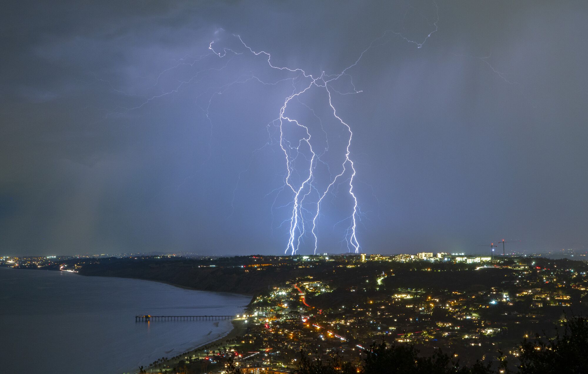 Lighting strikes the ground in north San Diego County with La Jolla in the foreground as seen from Mt. Soledad.