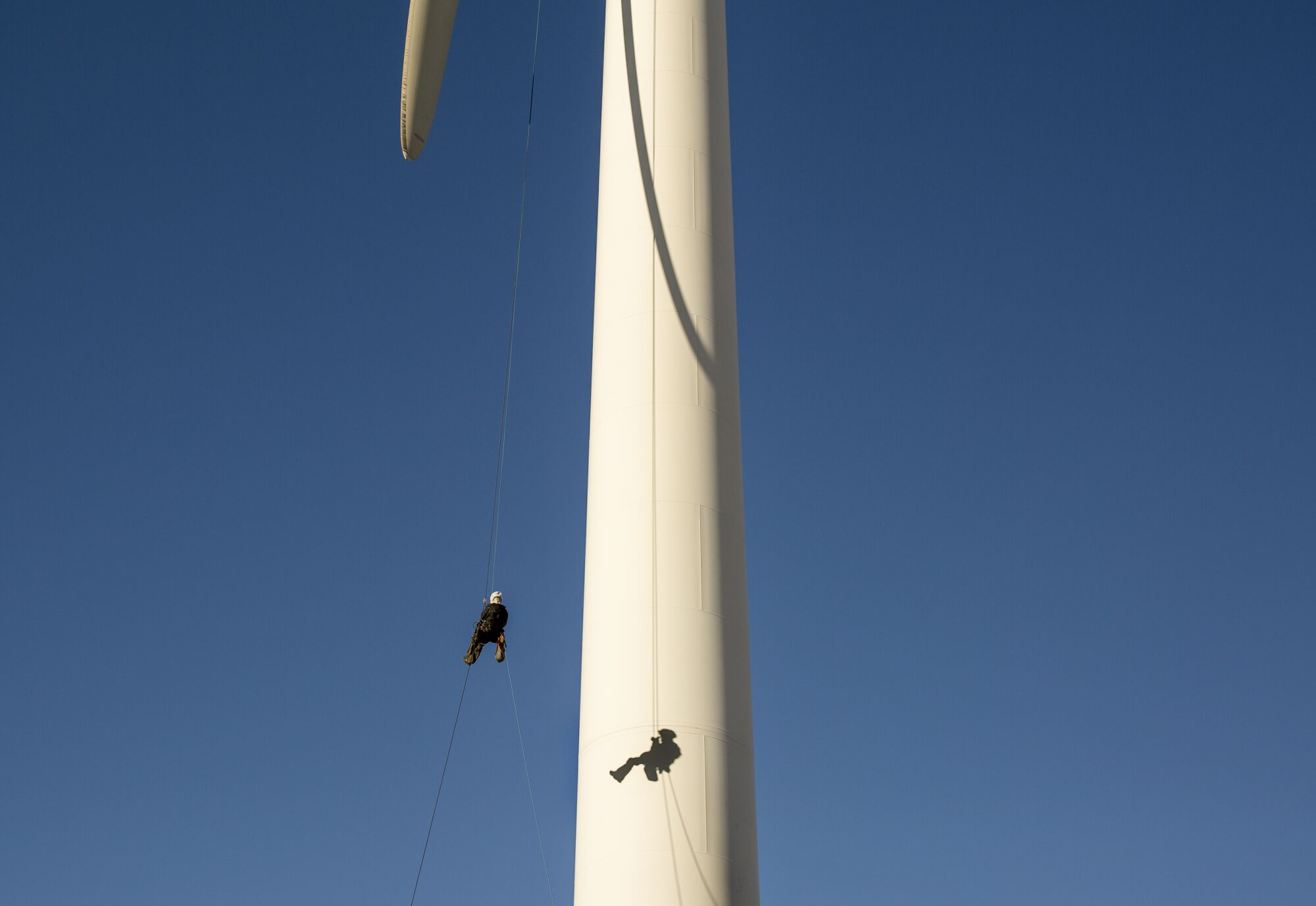 A person hangs from a wind turbine.