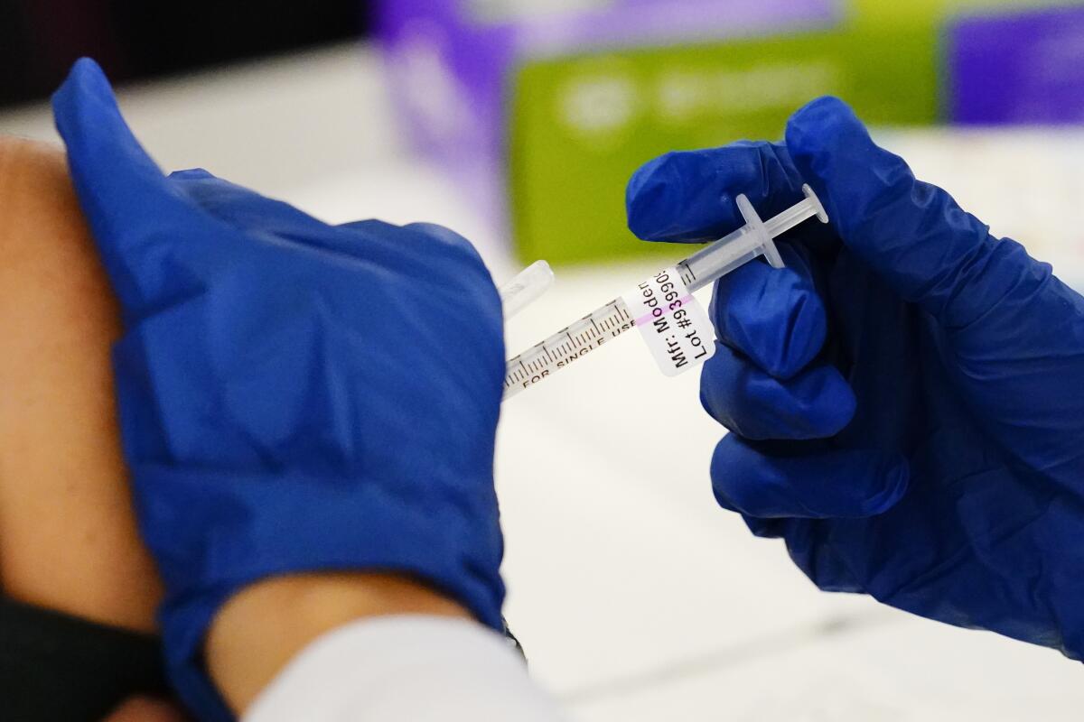 A health worker administers a dose of a Moderna COVID-19 vaccine. 