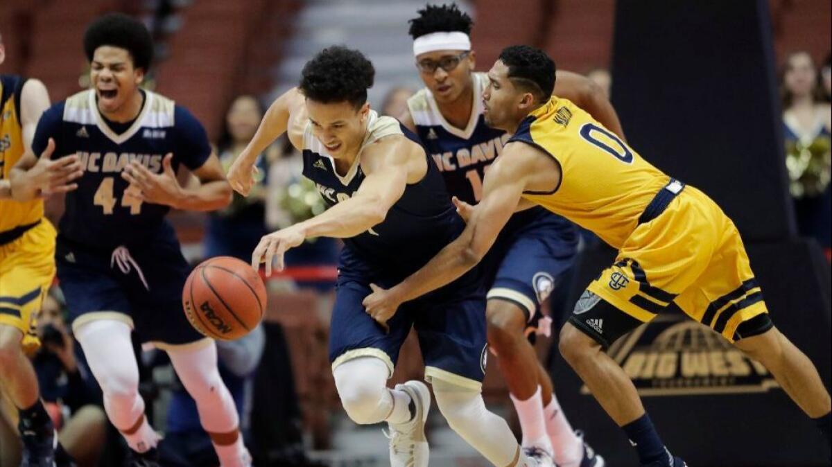 UC Davis' Lawrence White grabs a loose ball in front of UC Irvine's Jaron Martin during the first half of the Big West tournament final on March 11.