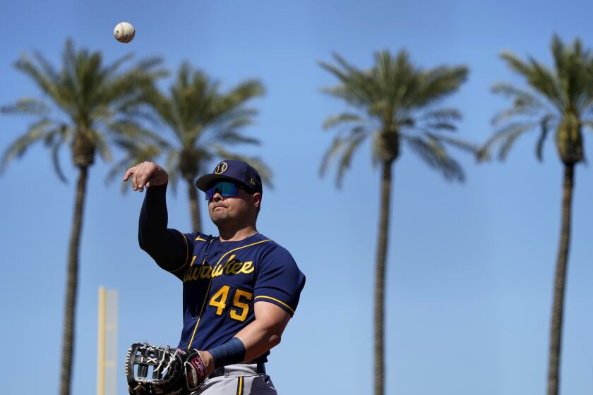Milwaukee Brewers' Luke Voit throws a ball to a fan during the second inning of a spring training baseball game against the Cincinnati Reds, Monday, March 13, 2023, in Goodyear, Ariz. (AP Photo/Matt York)