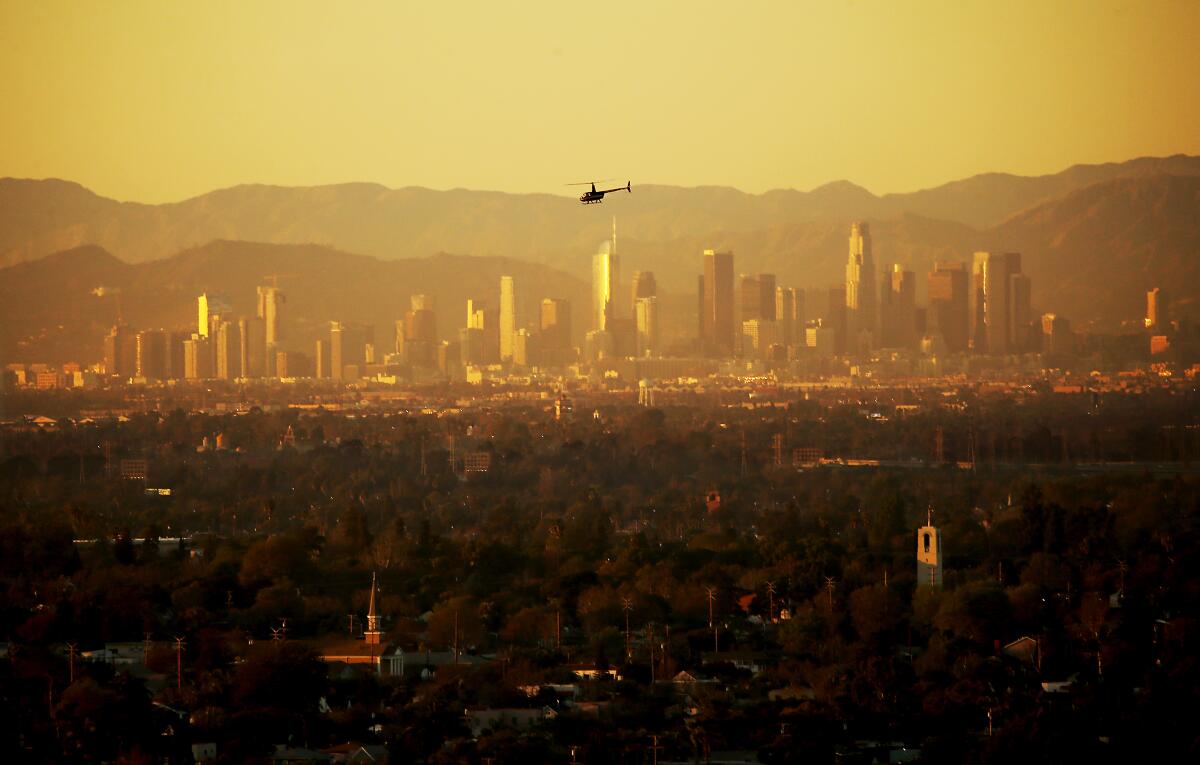 A helicopter above a hazy yellow cityscape.