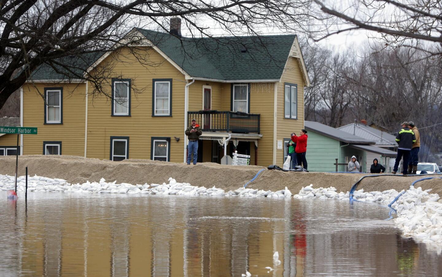 People hang out by the recently built-up levees holding rising Mississippi River waters at bay in Kimmswick, Mo., on Dec. 31, 2015.