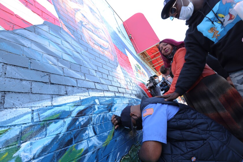 Terrence Floyd, the brother of George Floyd, kneels as he takes a moment in front of his brother's mural.