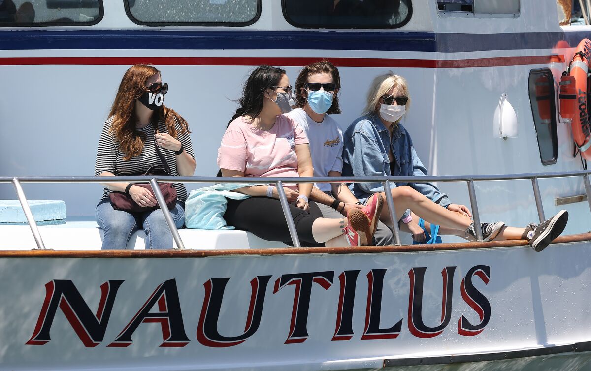 Patrons return from a whale-watching trip aboard the Nautilus while wearing face coverings in Newport Beach on Monday.