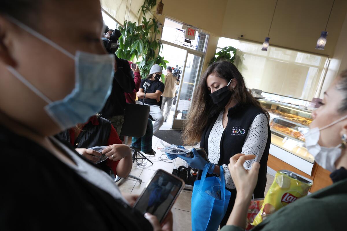 A San Mateo County Office of Community Affairs specialist hands out protective face masks to people in Daly City.