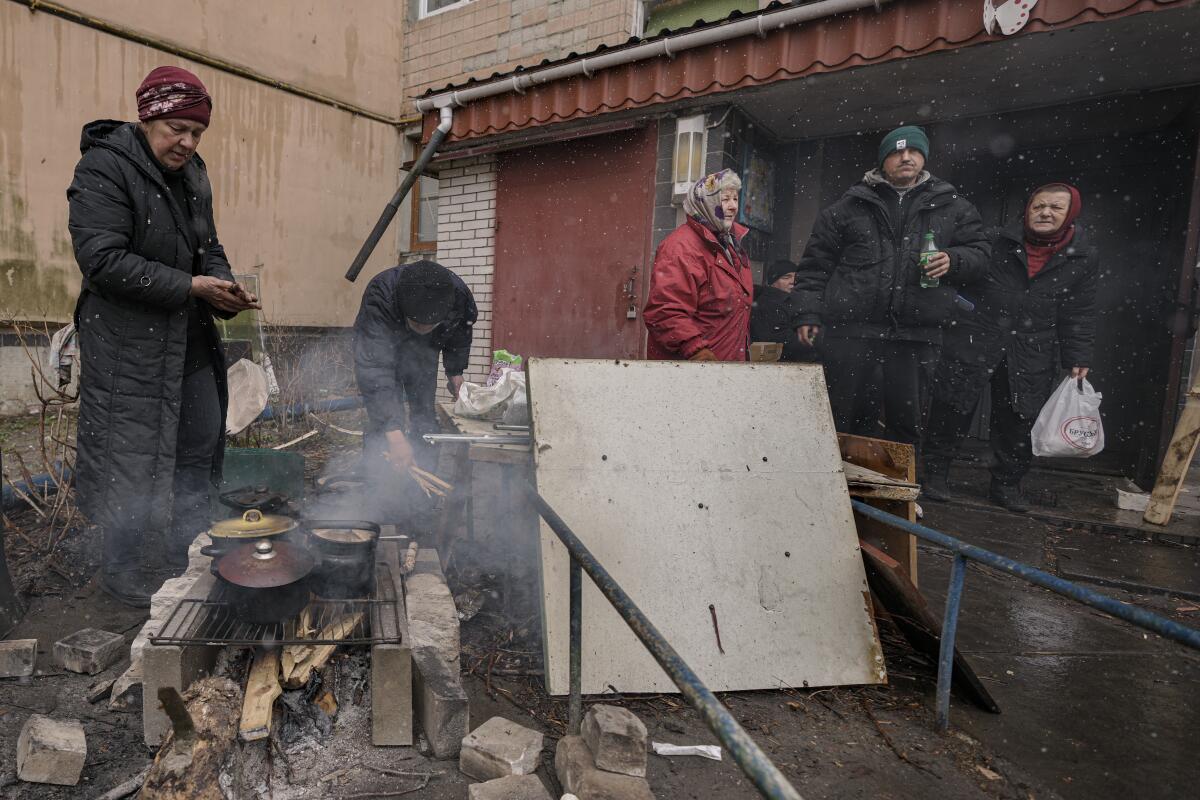 People cook on an open fire outdoors.