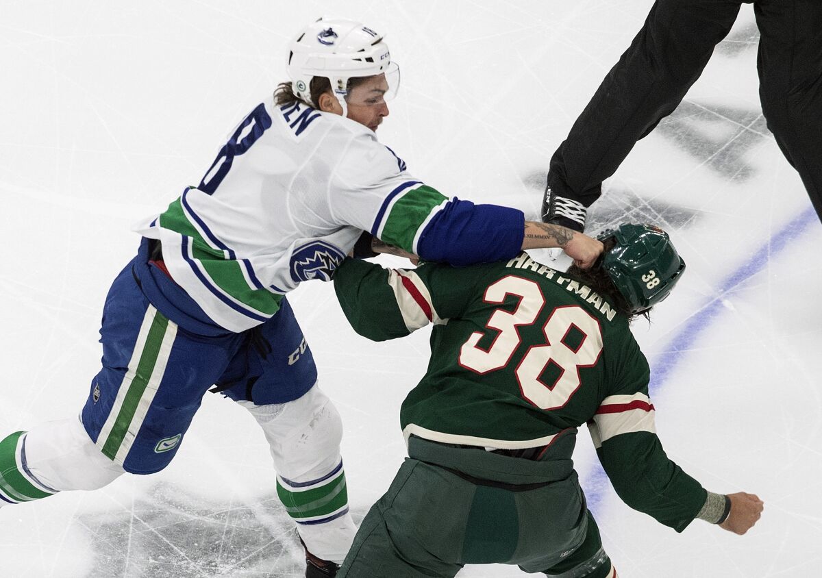 Minnesota Wild's Ryan Hartman (38) and Vancouver Canucks' Jake Virtanen (18) fight during the first period of an NHL hockey playoff game Friday, Aug. 7, 2020, in Edmonton, Alberta. (Jason Franson/Canadian Press via AP)
